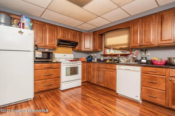a kitchen with granite countertop wooden cabinets and white appliances