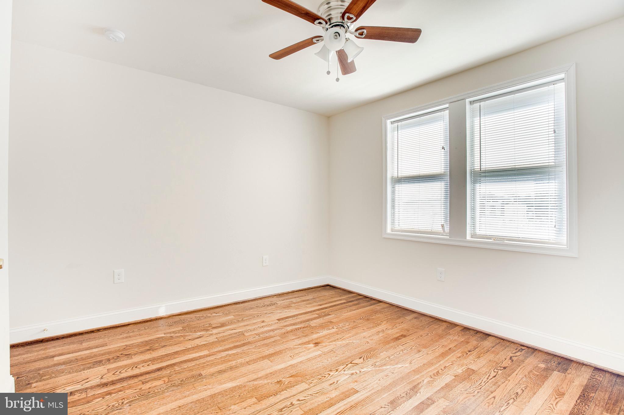 149 Denison Street, Unit 2 Baltimore, MD 21229 - Photo 16 of 19 an empty room with wooden floor fan and windows
