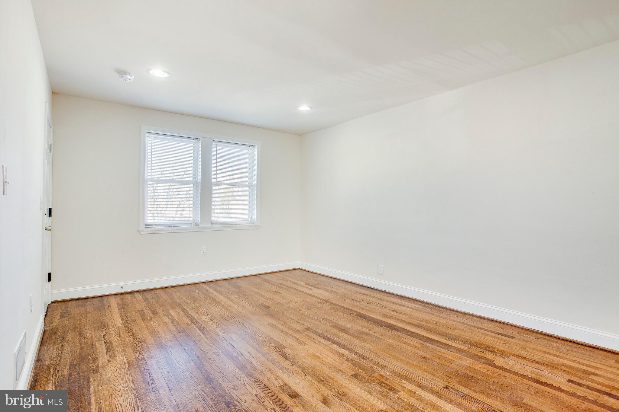 149 Denison Street, Unit 2 Baltimore, MD 21229 - Photo 4 of 19 an empty room with wooden floor and windows