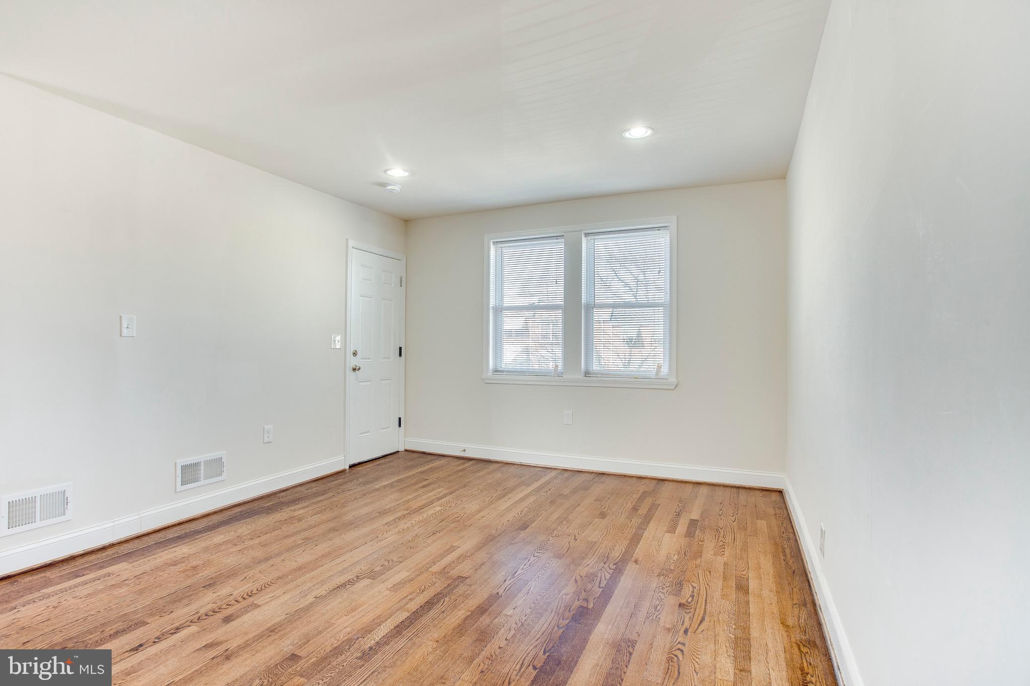 149 Denison Street, Unit 2 Baltimore, MD 21229 - Photo 6 of 19 an empty room with wooden floor and windows