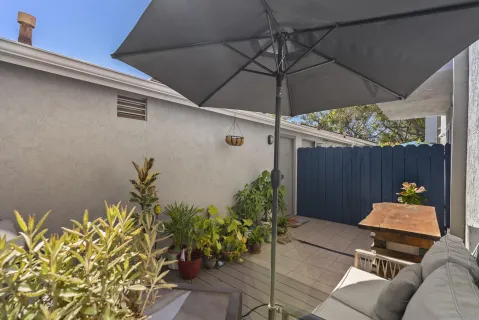 a backyard of a house with table and chairs under an umbrella