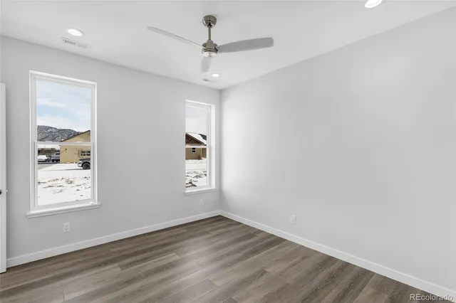 a view of an empty room with a window and wooden floor
