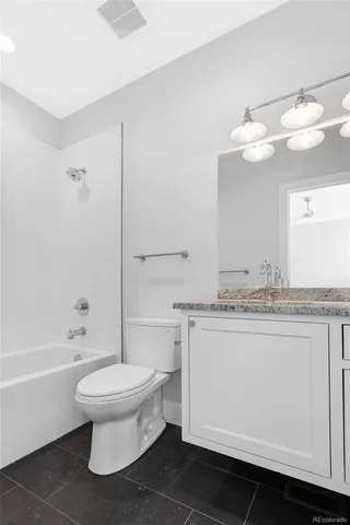 a bathroom with a granite countertop sink a toilet and bathtub
