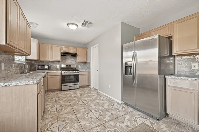 a kitchen with granite countertop a refrigerator and a stove top oven