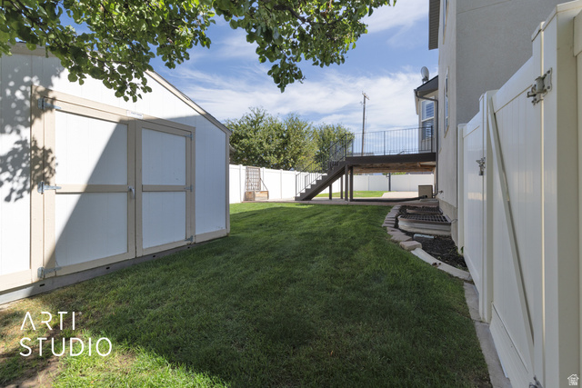 704 West Vahe Street Draper, UT 84020 - Photo 29 of 35 Expansive lawn featuring a storage shed, vinyl fencing, and a raised wood-finish deck with metal railings
