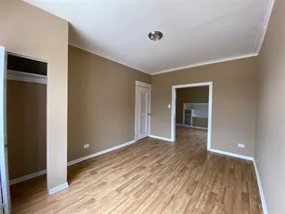 a view of an empty room with wooden floor and closet