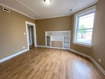 a view of an empty room with a window and wooden floor