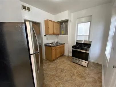 a kitchen with stainless steel appliances a refrigerator a stove a sink and a window