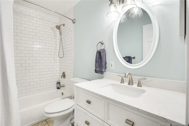 a bathroom with a sink vanity mirror toilet and bathtub