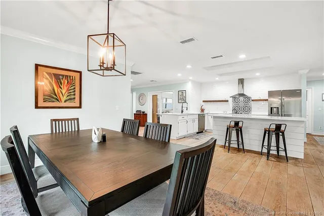 a open dining room with wooden floor a chandelier a wooden table and chairs