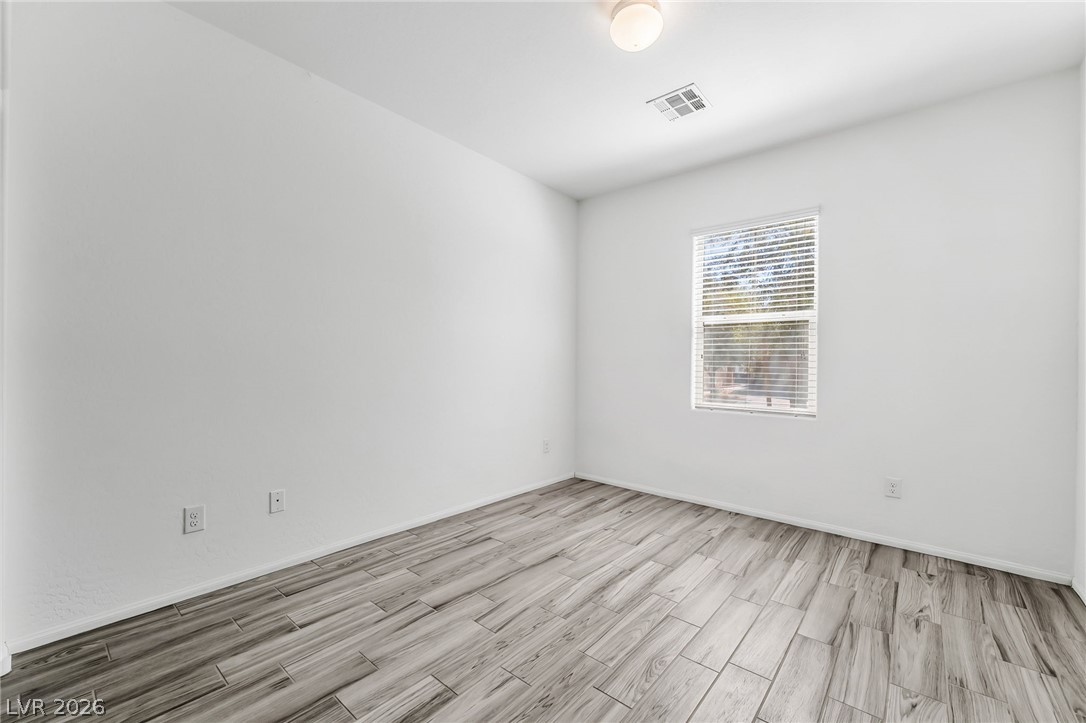 6245 Andover Wood Road Las Vegas, NV 89113 - Photo 28 of 37 A well-lit bedroom featuring durable plank tile flooring and a view of exterior foliage.