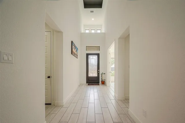 a view of a hallway with wooden floor and a bathroom