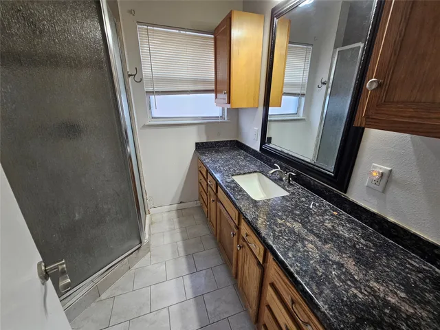 a bathroom with a granite countertop sink a mirror and a shower