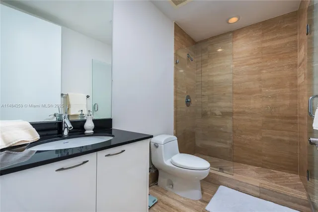 a bathroom with a granite countertop sink a toilet and shower