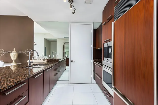 a large kitchen with granite countertop a sink and stainless steel appliances