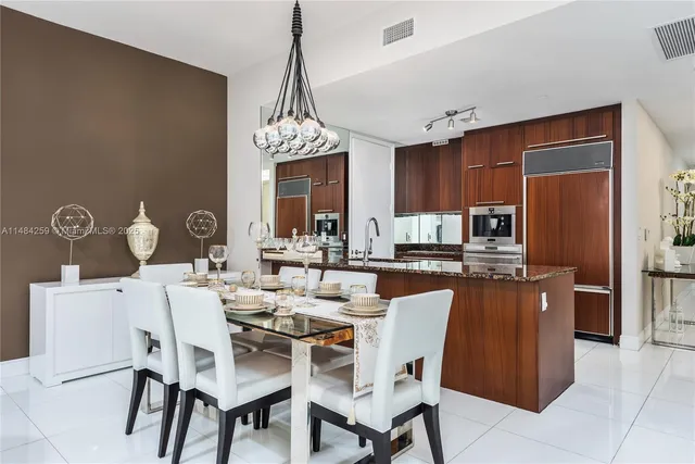 a dining room with furniture a chandelier and kitchen view