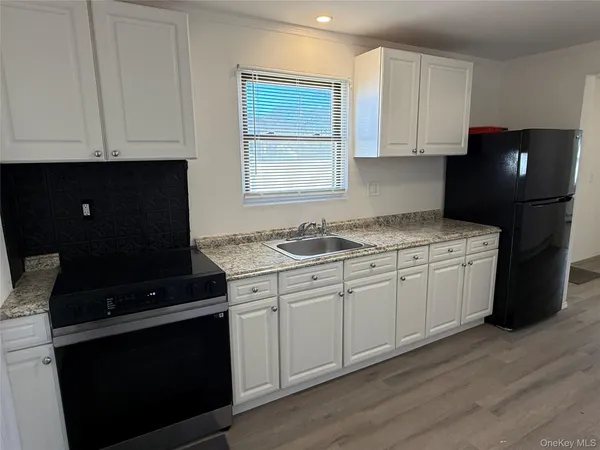 a kitchen with granite countertop white cabinets and black appliances