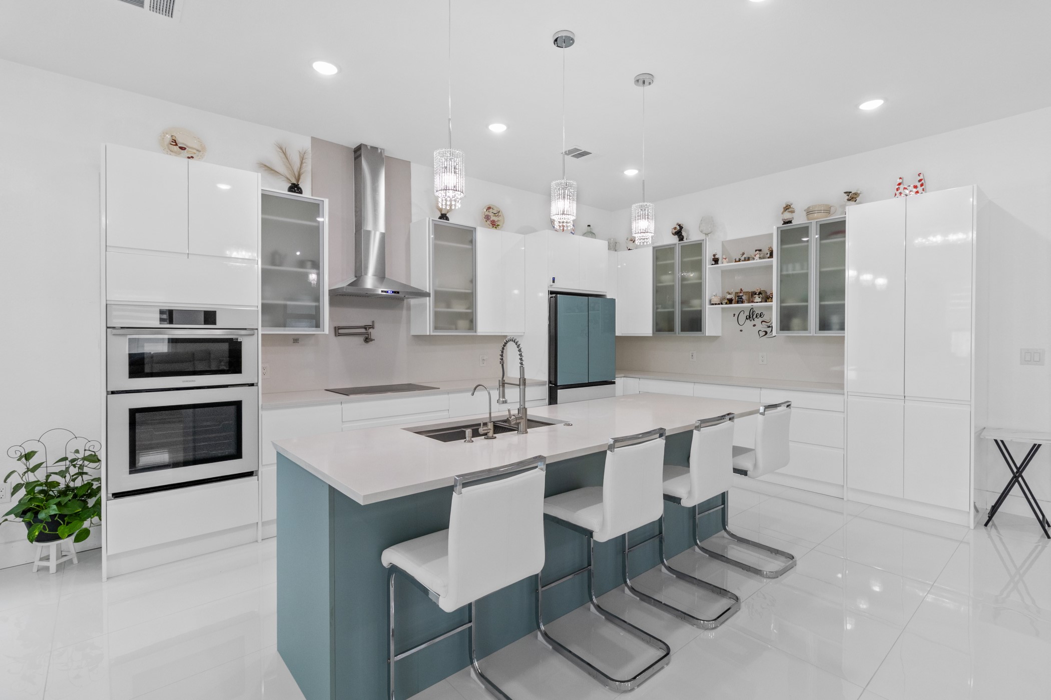 123 Zacate Street Elgin, TX 78621 - Photo 20 of 33 Bright kitchen featuring a central island with seating, white gloss cabinetry, integrated stainless steel appliances, and sleek pendant lighting