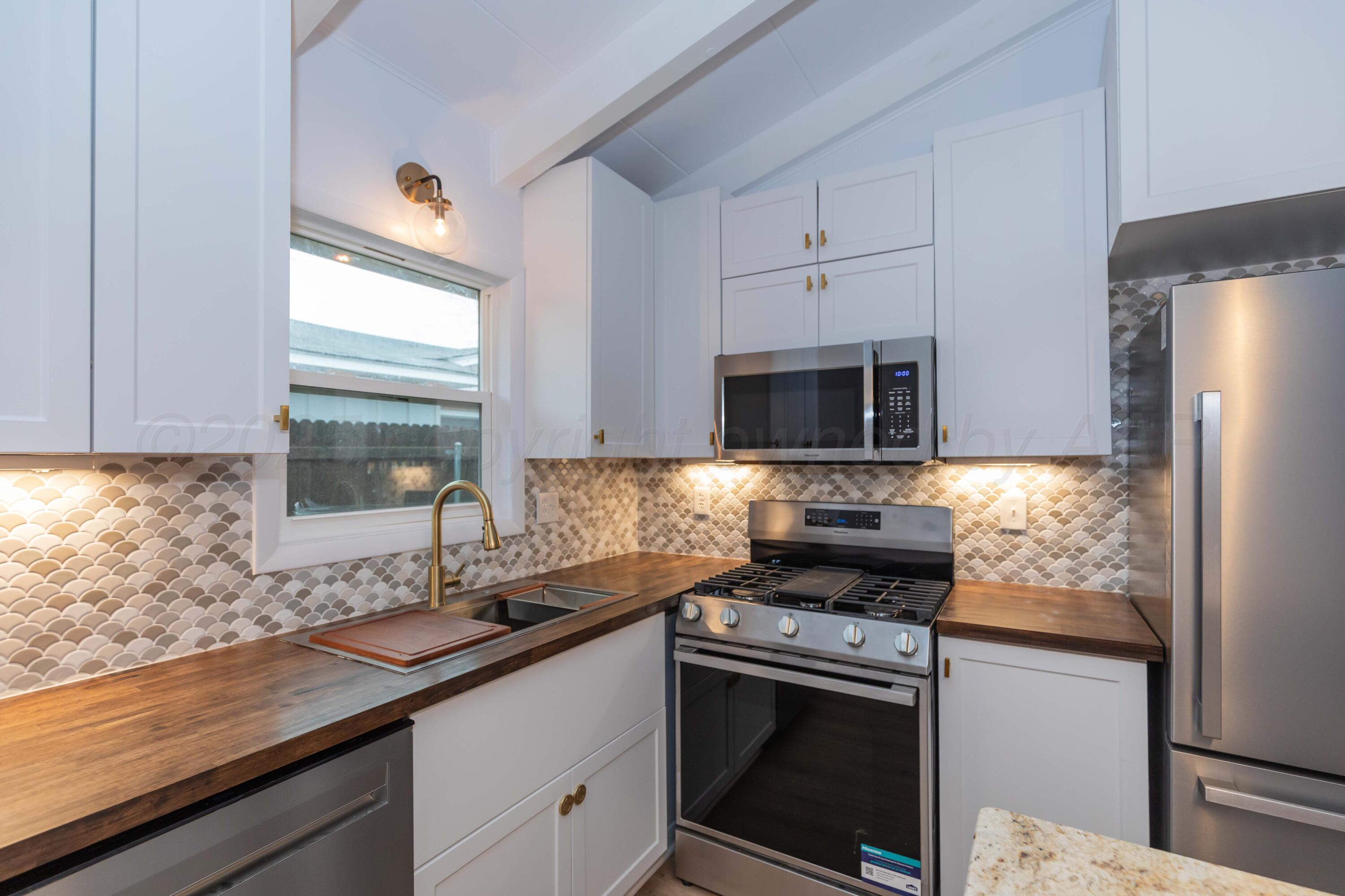 a kitchen with stainless steel appliances a stove a sink and a microwave