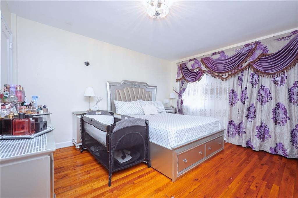 8844 18th Avenue Brooklyn, NY 11214 - Photo 16 of 19 a bedroom with a bed and a chandelier