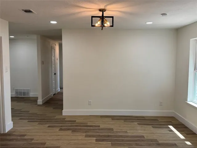 an empty room with wooden floor fireplace and windows