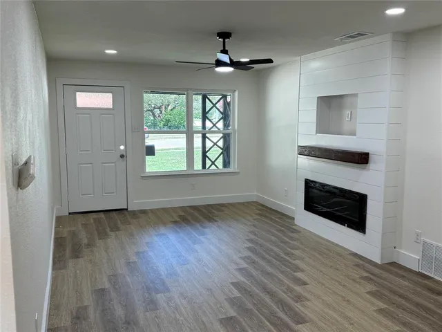 an empty room with wooden floor cabinet and windows