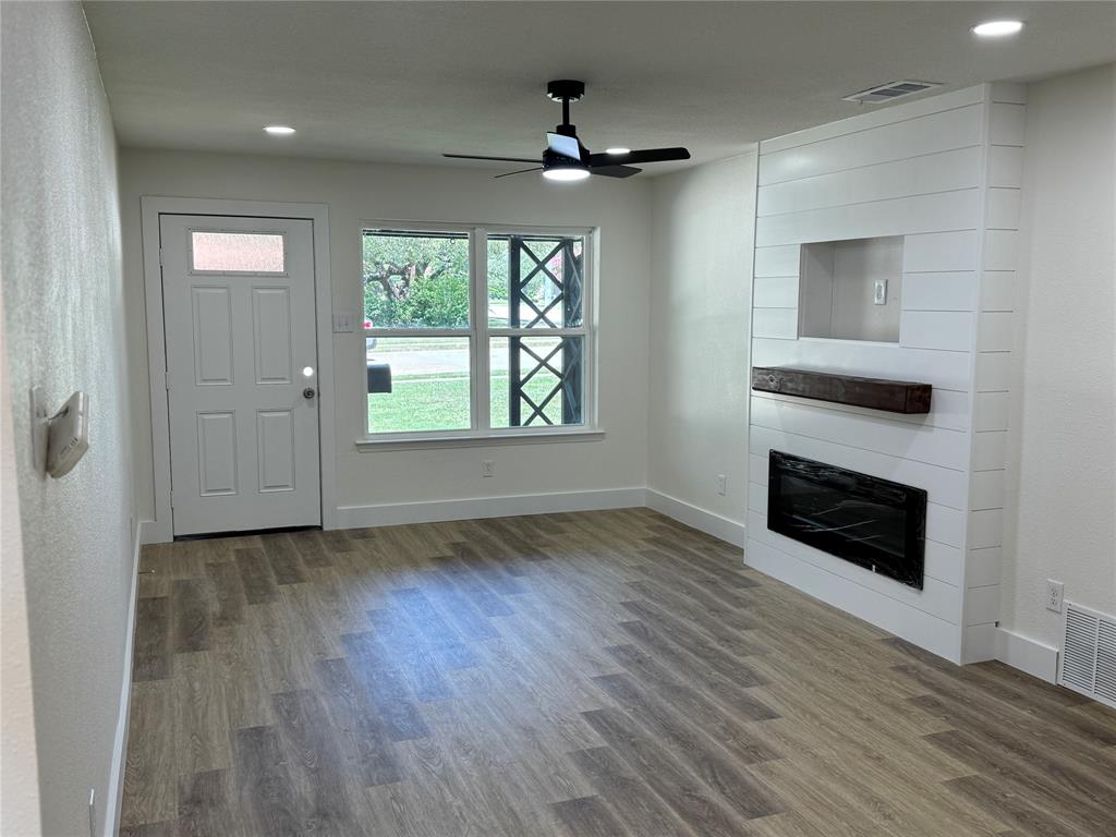 501 Cambridge Drive Richardson, TX 75080 - Photo 21 of 35 an empty room with wooden floor fireplace and windows