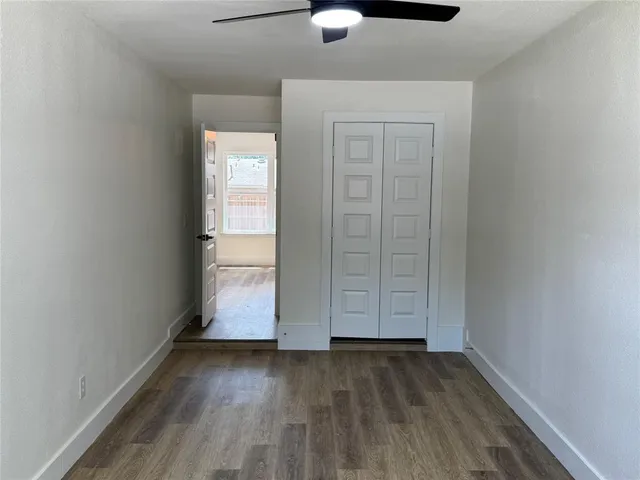 a view of a hallway with wooden floor and a bathroom