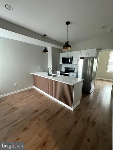 a kitchen with stainless steel appliances granite countertop a refrigerator a sink a stove and a wooden floors