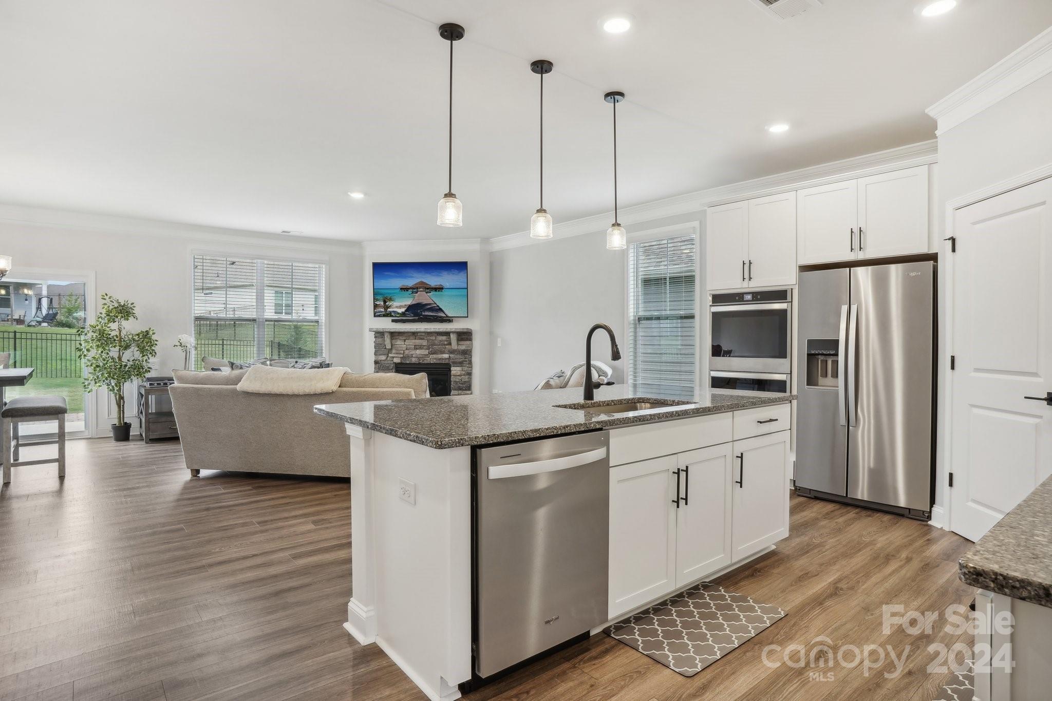 4203 Millstream Road Denver, NC 28037 - Photo 6 of 31 a kitchen with stainless steel appliances granite countertop a sink a stove a refrigerator and island with wooden floor