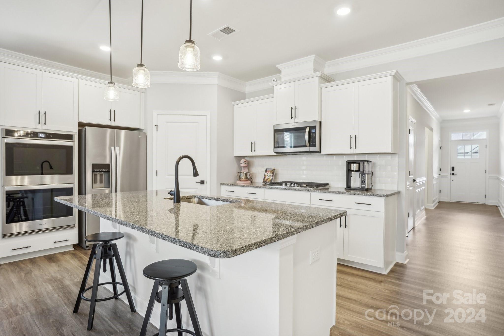4203 Millstream Road Denver, NC 28037 - Photo 7 of 31 a kitchen with stainless steel appliances granite countertop a sink a stove a refrigerator and island with wooden floor