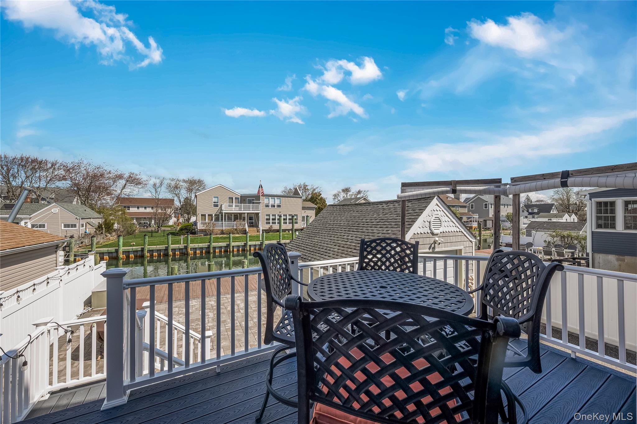 25 Cape Road Amityville, NY 11701 - Photo 24 of 30 a view of a roof deck with table and chairs with wooden floor and fence
