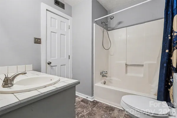 a bathroom with a granite countertop sink toilet and shower