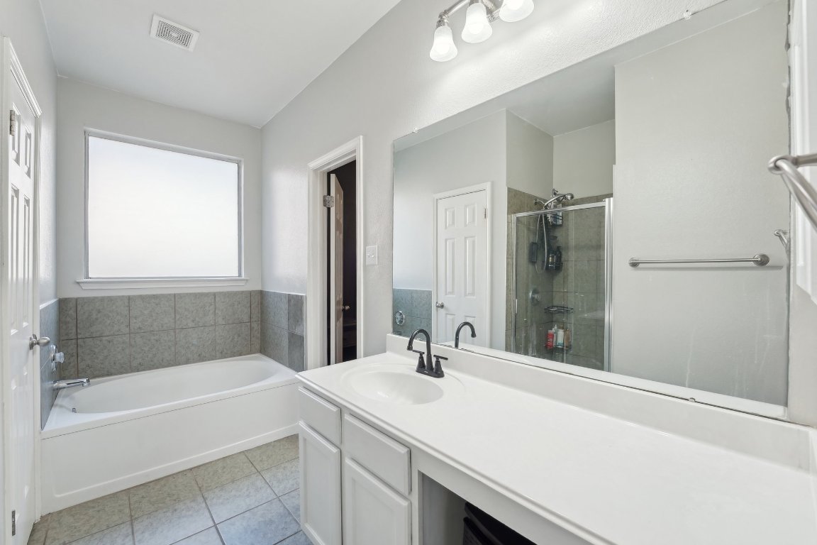 504 Chaparral Drive Leander, TX 78641 - Photo 16 of 34 a bathroom with a tub sink and mirror