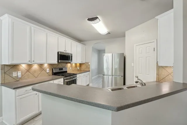 a kitchen with stainless steel appliances a sink a stove a microwave and cabinets