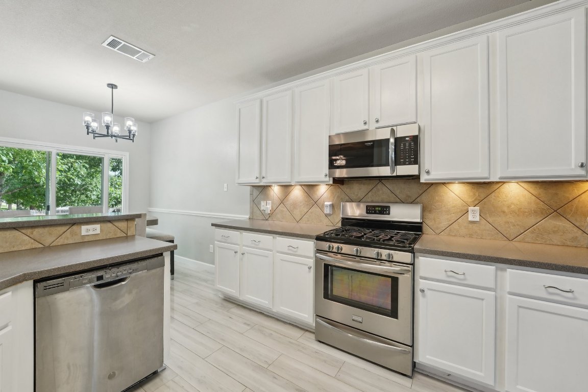 504 Chaparral Drive Leander, TX 78641 - Photo 9 of 34 a kitchen with granite countertop a stove a sink and a microwave