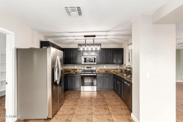 a kitchen with stainless steel appliances granite countertop a stove a refrigerator and a sink