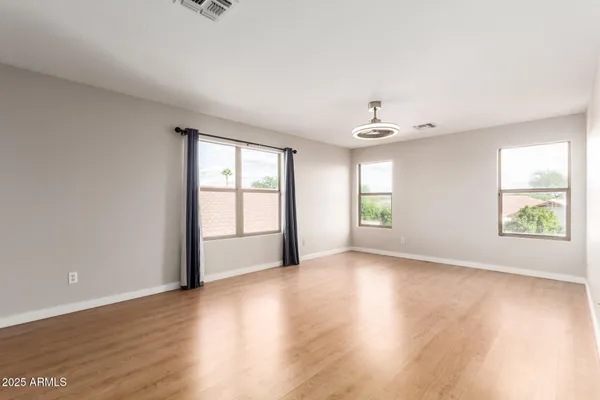 an empty room with wooden floor and windows