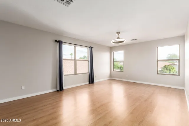 an empty room with wooden floor and windows