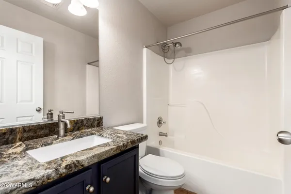 a bathroom with a granite countertop sink a toilet and shower