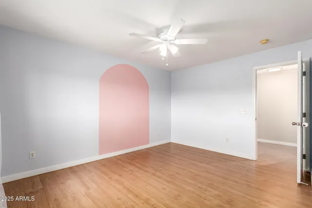 an empty room with wooden floor and fan