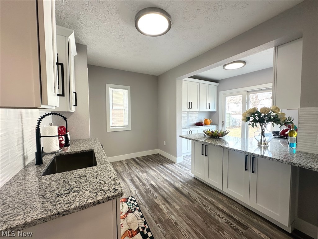 3409 Cedarbrook Road Cleveland Heights, OH 44118 - Photo 8 of 16 Kitchen with white cabinetry, tasteful backsplash, light stone countertops, dark wood-style flooring, and a textured ceiling
