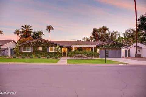 a front view of a house with a yard and palm trees