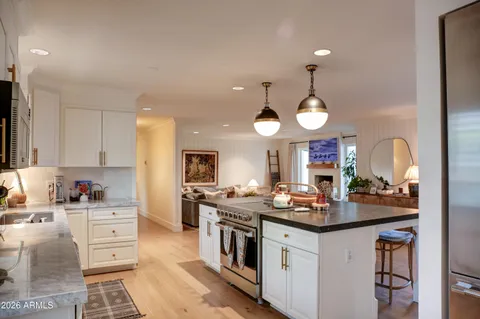 a kitchen with a stove a sink a refrigerator and a dining table with wooden floor