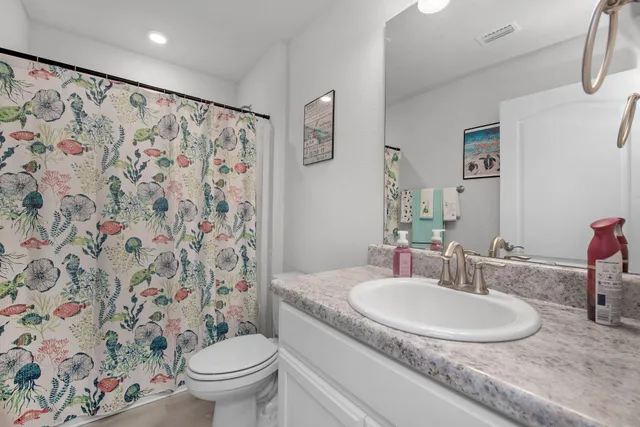 a bathroom with a granite countertop sink a toilet and a mirror