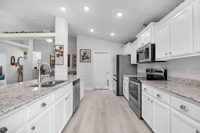 a large kitchen with stainless steel appliances granite countertop a lot of counter space and wooden floors