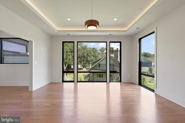 a view of an empty room with wooden floor and a kitchen