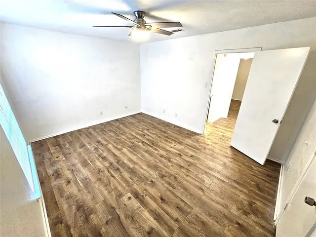 en empty room with wooden floor and fan