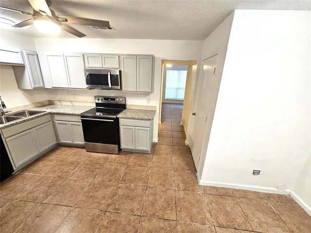 a large kitchen with stainless steel appliances granite countertop a stove top oven a sink and dishwasher