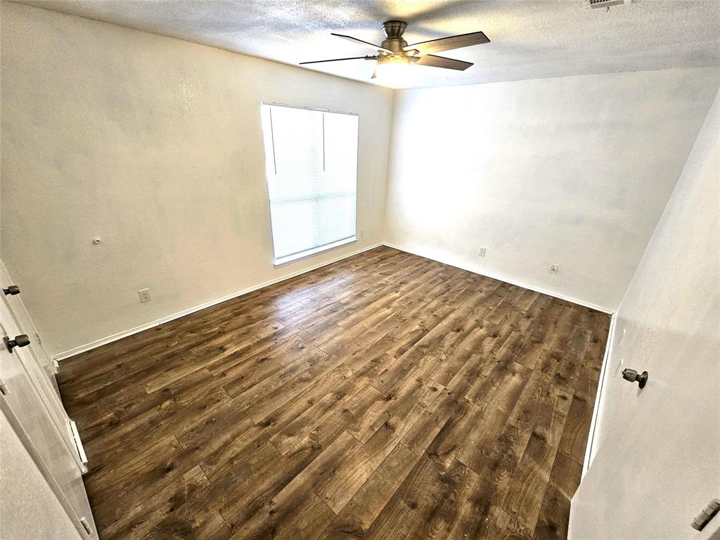 724 Bluebonnet Drive, Unit A Keller, TX 76248 - Photo 10 of 27 en empty room with wooden floor and fan
